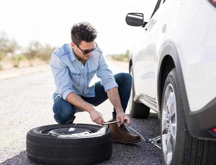 Automobilista in sosta per cambiare pneumatico forato. Il ladro approfitta del finestrino abbassato per rubare il borsello e carte di credito.
